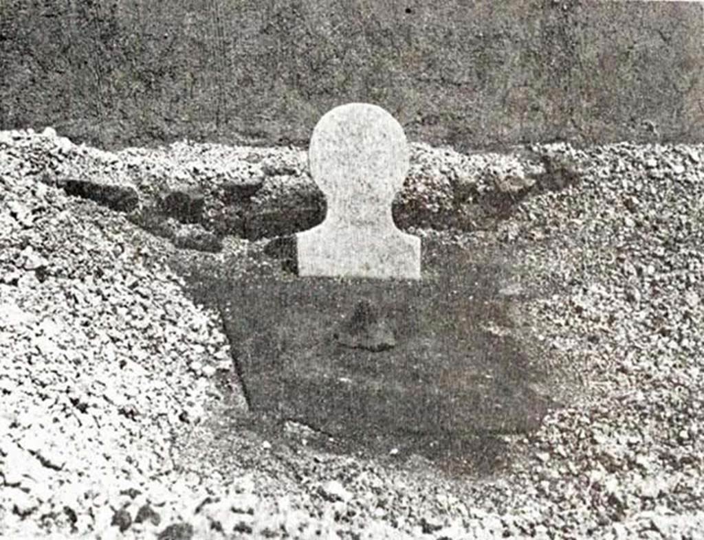 NGOF Pompeii. 1976. The burial in the north-east  of the tomb.
According to Stefano de Caro, a marble columella in human shape, but without an inscription, indicated the place of the burial.
In front of this were two tiles lying flat and upside down on a thin bed of mortar.
Near the columella was a hole in the centre, protected, with the tip of an amphora.
Below it was the mouth of a terracotta tube used for the libations. 
Alongside this, at a depth on 20cm below the tomb floor, was a clear blue glass cinerary urn, in fragments, fitted with a matching lid and with handles in the shape of an “M”.
See De Caro S., 1976. Scavi nell’area fuori Porta Nola a Pompei: Cronache Pompeiane V, figs. 8-9, pp. 71-3.
