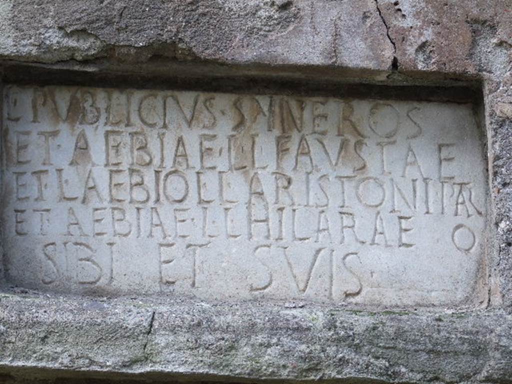 Pompeii Porta Nocera. Tomb 22EN. May 2006.
Tomb of Lucius Publicius Syneros, Aebia Fausta, Lucius Aebius Aristo and Aebia Hilara.

Plaque with latin inscription:
L(ucius)  PVBLICIVS  SYNEROS
ET  AEBIAE  L(uci)  L(ibertae)  FAVSTAE
ET  L(ucio)  AEBIO  L(uci)  L(iberto)  ARISTONI  PATR(i)
ET  AEBIAE  L(uci)  L(ibertae)  HILARAE
SIBI  ET  SVIS.

There is an extra O, at the end of the fourth line, after HILARAE.



