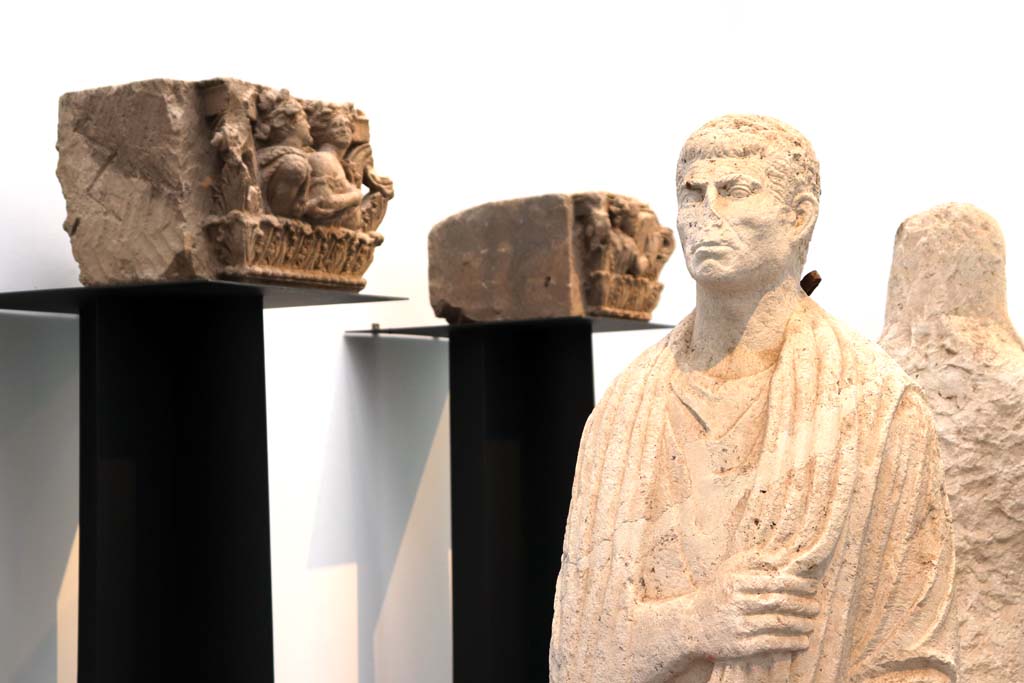 Porta Nocera tombs 34aEN. February 2021. 
Detail of limestone funerary statue of a man wearing a toga, on display in Antiquarium.
Photo courtesy of Fabien Bièvre-Perrin (CC BY-NC-SA).
