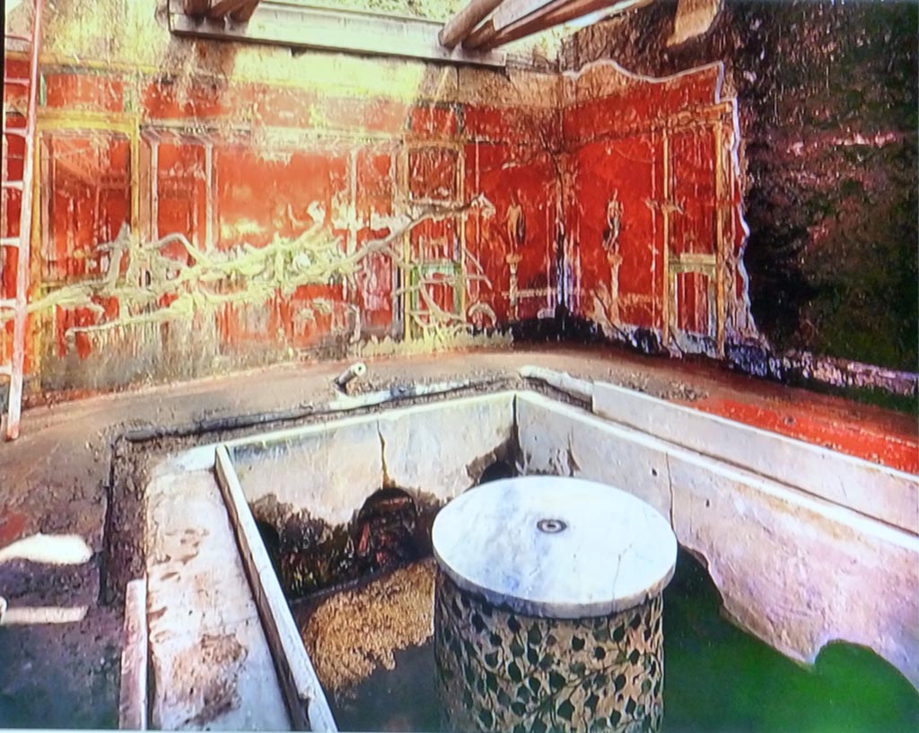 Complesso dei triclini in località Moregine a Pompei. 1959 excavation photo. On display in Pompeii Palaestra September 2015. 
Triclinium C. North and east walls in situ with marble clad triclinium and round table with plant decorations.
Water channels run around the sides of the triclinium and remains of a water jet can be seen at the rear.
Water was a problem during excavation as the complex was below the water table after the eruption, though this had also helped preserve some items.

