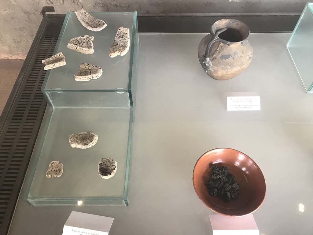 Complesso dei triclini in località Moregine a Pompei. April 2019. Finds.
Top right: Copper jug with handle in the form of a thumb.
Left: Cork sandal soles.
Bottom right: Walnuts.
Photo courtesy of Rick Bauer.
