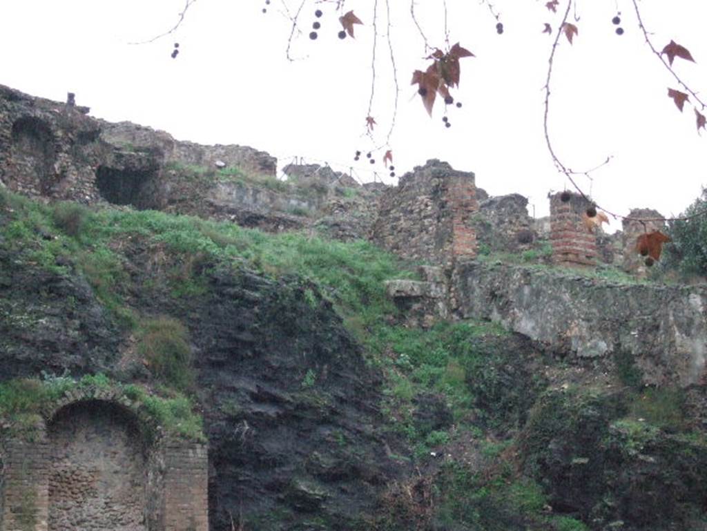 VIII.2.29 and VIII.2.30 Pompeii from rear. December 2006.
According to the drawing of the plan in PPM –
the stairs from the area of the kitchen down to a terrace would have been at the side of the brick pilaster, centre right.
According to Van der Graaf –
“The defences on this side of the city functioned primarily as a terrace and lacked the agger. …………..
Terrace 20 in House VIII.2.29, in particular, displays two tuff blocks that still carry masonry marks. They flank a lonely travertine block still in situ.”
See Van der Graaff, I. (2018). The Fortifications of Pompeii and Ancient Italy. Routledge, (p.49).

